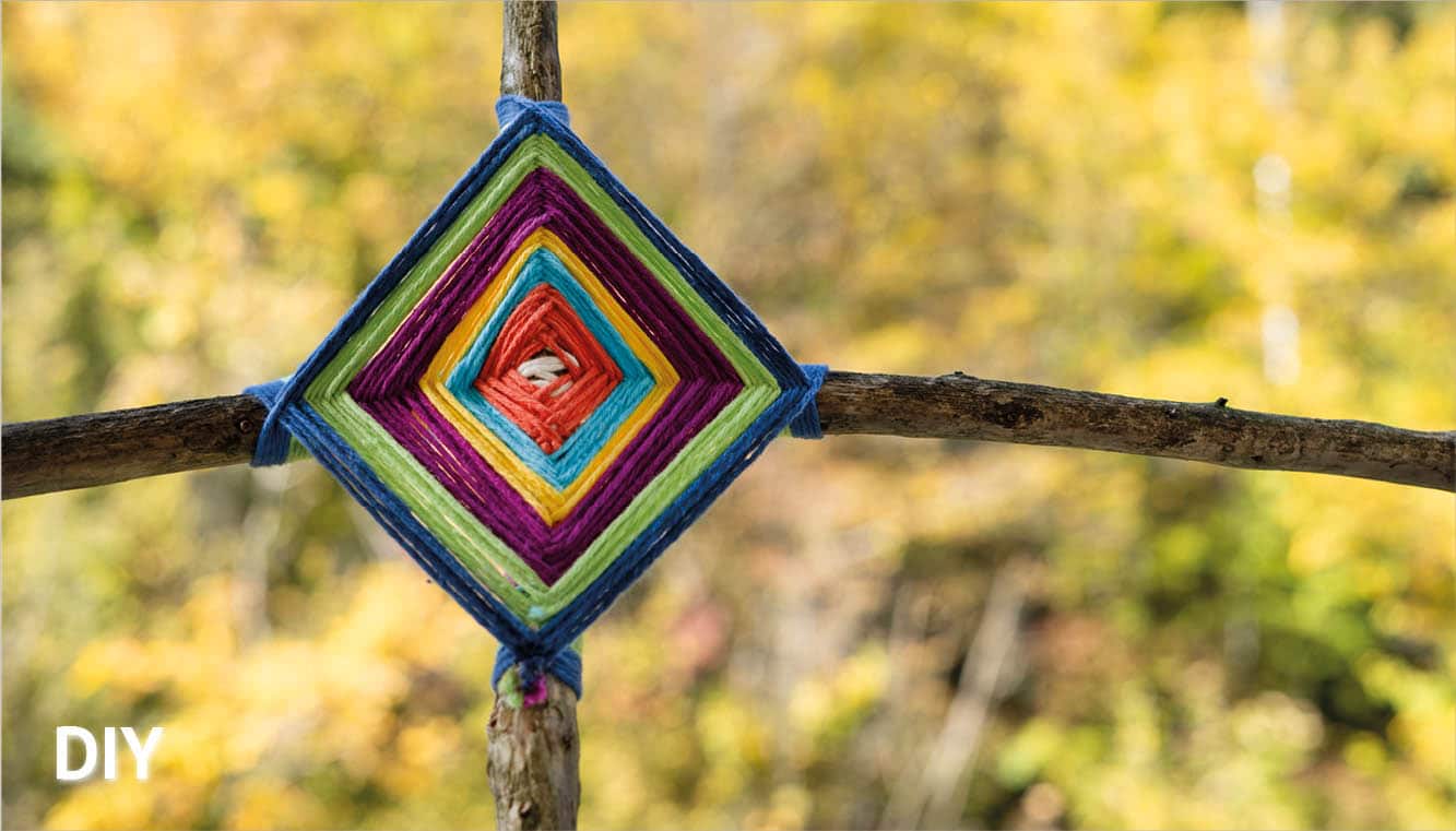 Buntes Holzkreuz vor Wald