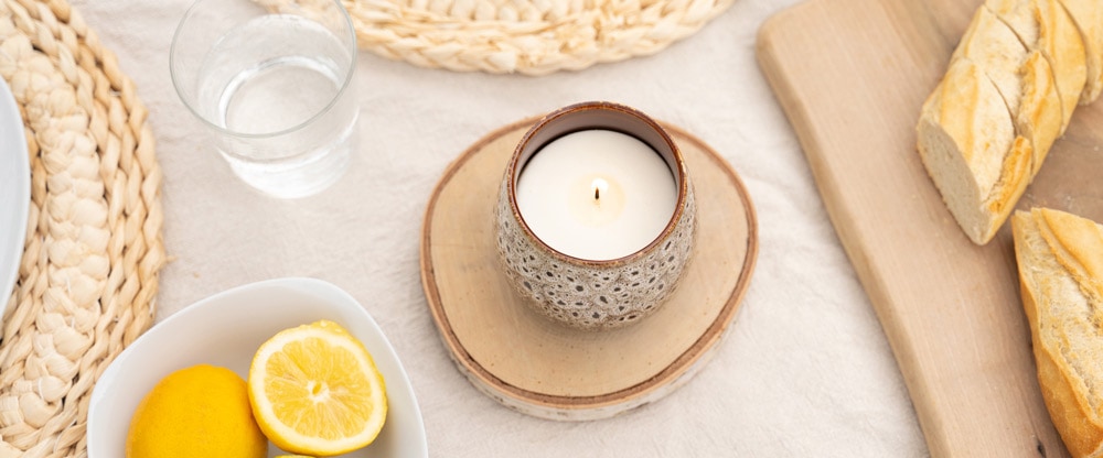 Gedeckter Tisch mit angezündeter Kerze im Keramiktopf