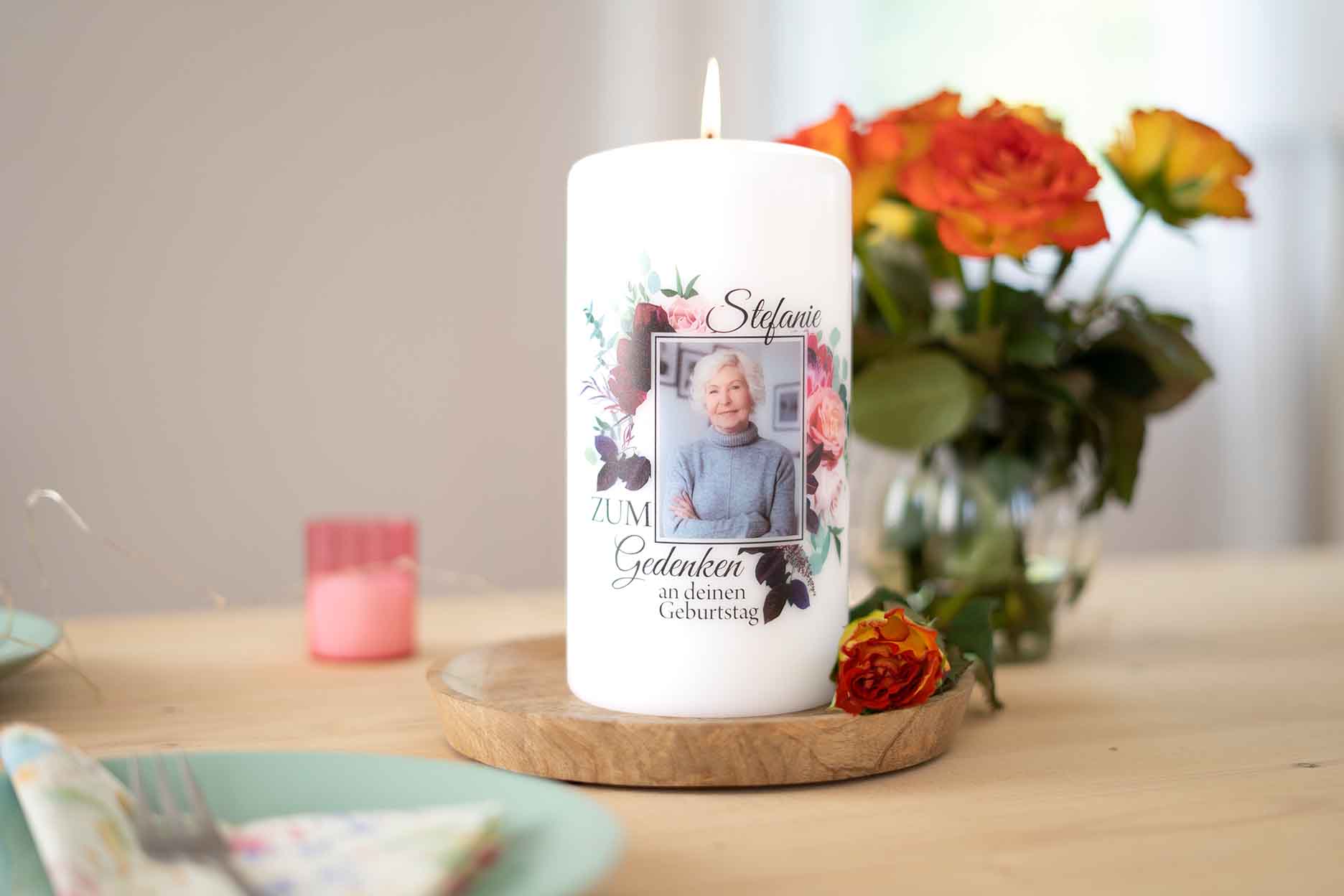 eine selbstgestaltete Gedenkkerze auf einem Tisch neben einem Blumenstrauß