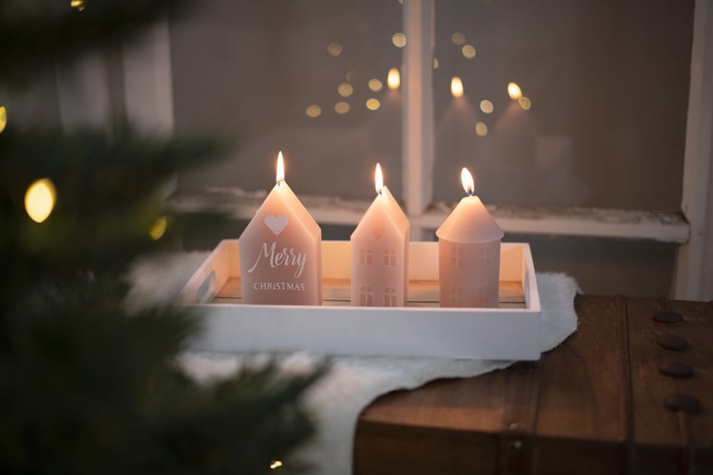 Rosafarbene Dekokerzen vor Fenster und Christbaum