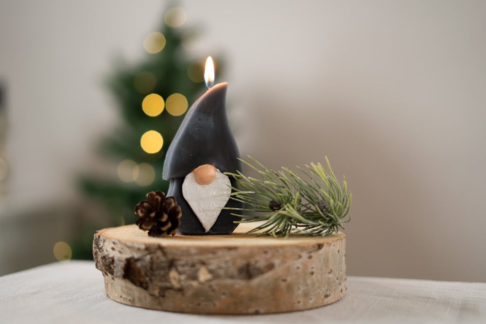 Advent-Rätsel 1 Lösung Wichtelkerze mit weihnachtlicher Deko und Christbaum im Hintergrund